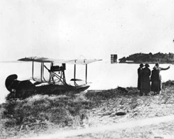 historic photo of old sea plane on the ocean shore.